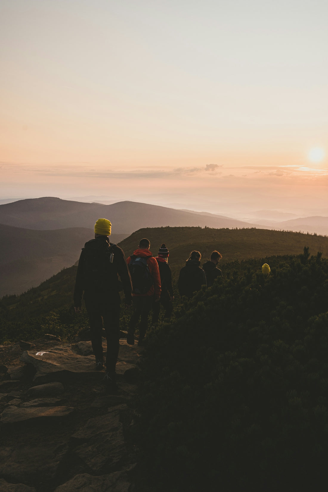 people walking on rocky mountain during sunset
